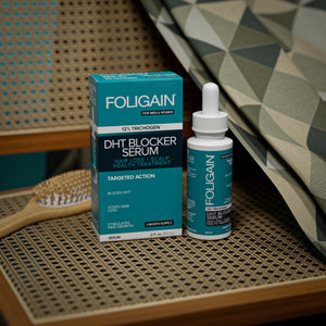 زجاجة وعلبة سيروم FOLIGAIN المثبط لـ DHT على مقعد كرسي منسوج.