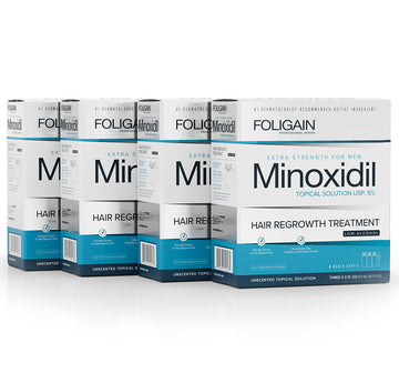 علب محلول مينوكسيديل FOLIGAIN الموضعي للرجال بتركيز 5% في عبوات زرقاء وبيضاء للتركيبة منخفضة الكحول.