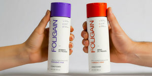 يدان تحملان بلسم FOLIGAIN TRIOXIDIL للنساء والرجال بأغطية بنفسجية وبرتقالية.