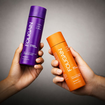 يدان تحملان عبوات شامبو FOLIGAIN TRIOXIDIL للنساء والرجال.