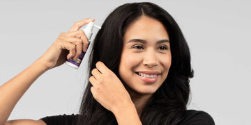 امرأة تضع علاج FOLIGAIN الموضعي على فروة رأسها باستخدام أداة رش.