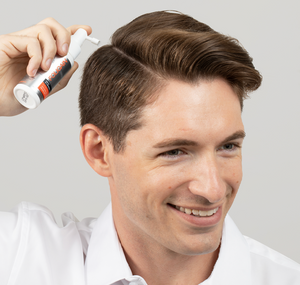 رجل يضع منتج FOLIGAIN الموضعي للعناية بالشعر على طول فرق شعره